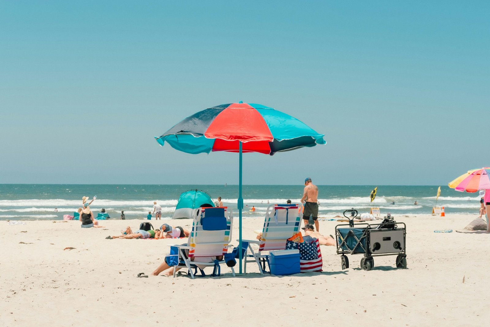 A sunny beach scene in Oceanside with umbrellas and sunbathers enjoying the sand and ocean view.